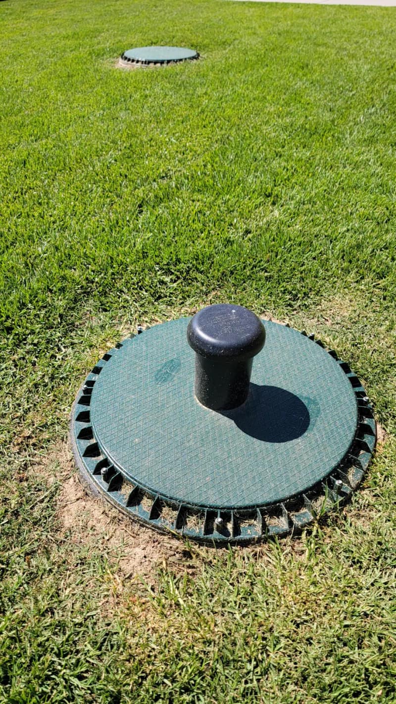 Finished septic riser lid set flush in a green lawn